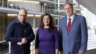 Auf dem Foto sind drei Personen im Bundestagsgebäude zu sehen